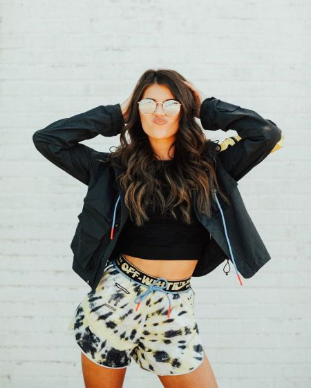 Madison Prewett in a black top and white shorts poses for a picture